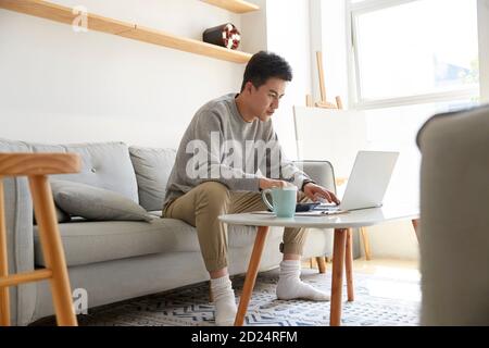 young asian corporate executive staying at home working using laptop computer Stock Photo
