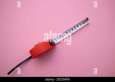 Red measuring tape on pink background, top view Stock Photo