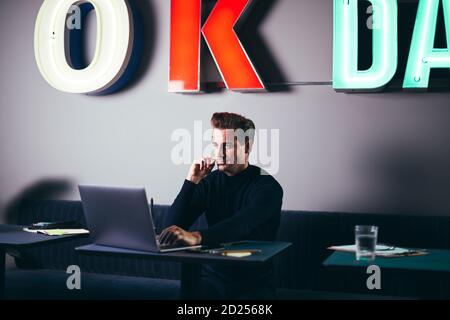 Focused young businessman using a laptop at a table while working in a shared office space Stock Photo