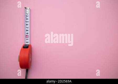 Industrial red measuring tape on pink background, top view. Free space for text Stock Photo