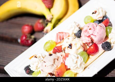 Plate of healthy fresh fruit salad with ice cream on the wooden background. Stock Photo