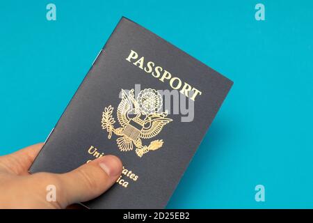 Hand holding US Passport on blue background Stock Photo