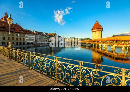 Cityscape of Lucerne on Lake Lucerne, Switzerland at sunset. Historic covered wooden footbridge, Chapel Bridge with Water Tower reflect on Reuss river Stock Photo