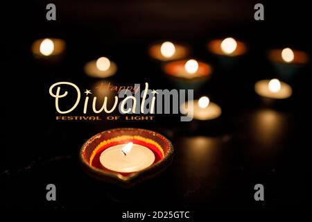 Happy Diwali - Clay Diya lamps lit during Dipavali, Hindu festival of lights celebration. Colorful traditional oil lamp diya on dark background. Copy Stock Photo