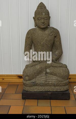 Close up view of grey buddah figure on white wall background. Stock Photo