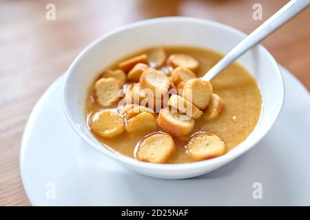 Vegetable soup with bread crumbs in a white bowl standing on a wooden table Stock Photo