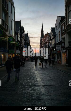 Christmas shoppers in Chester on Watergate Street's cobbles just as the sun sets Stock Photo