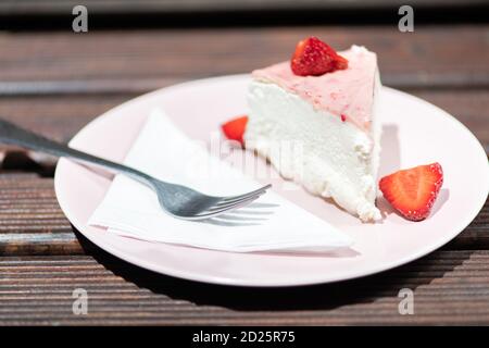 Slice of fresh strawberry tart on the pink plate with layered cream. Stock Photo