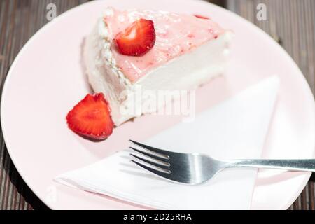 Slice of fresh strawberry tart on the pink plate with layered cream. Stock Photo