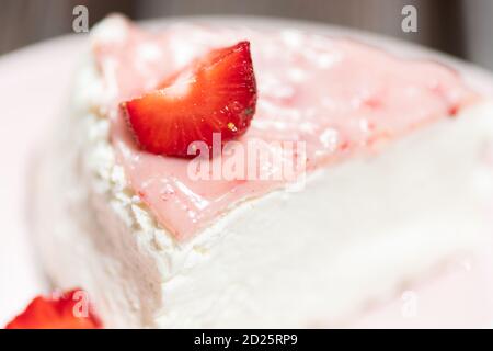 Close up of fresh strawberry tart slice on the pink plate with layered cream. Stock Photo