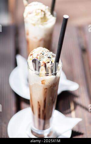 Ice coffee on a wood table with cream being poured into it showing the texture and refreshing look of the drink. Stock Photo