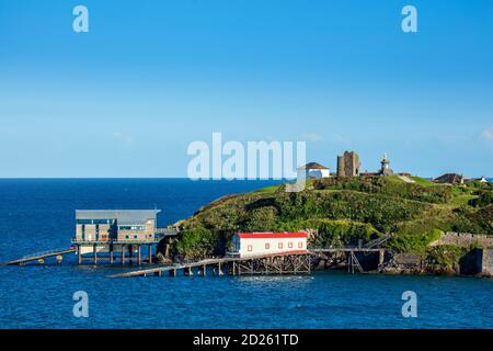 The old (foreground with a red roof) and new lifeboat stations (background with a grey roof) and the ruined castle in Tenby, Wales, UK Stock Photo