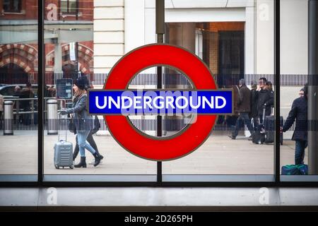 London, UK - February 2, 2020 - London underground sign at Kings Cross station with passing tourists Stock Photo