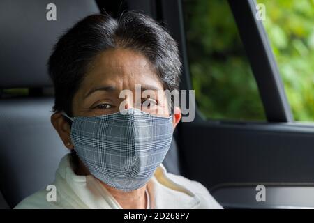 British Asian woman (BAME) wearing face mask in a car. COVID or Coronavirus concept, prevention and self-isolating in UK.