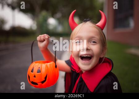 Little Girl in costume of devil with red horns in park. Happy Halloween concept Stock Photo