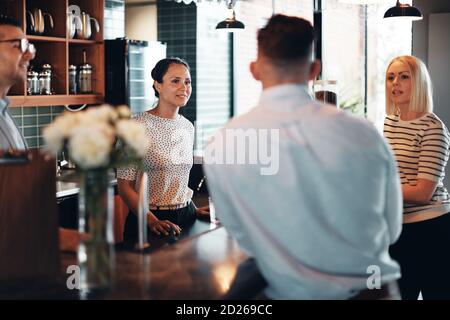 Smiling group of businesspeople talking together while standing in the lounge area of an office during a break Stock Photo