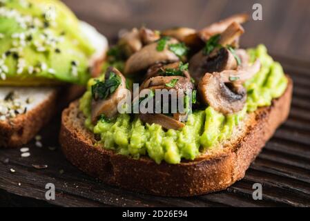 Tasty avocado toast with fried mushrooms and greens Stock Photo
