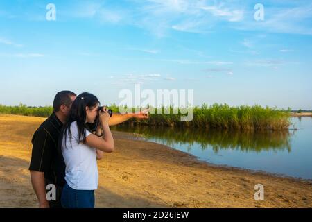 Photography lessons by the river in summer. The teacher shows a woman photographer how to take pictures. Stock Photo