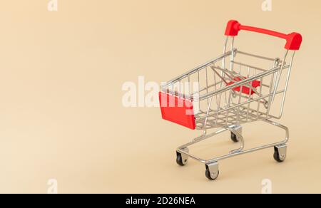 Empty red shopping cart or trolley on beige background with copy space Stock Photo