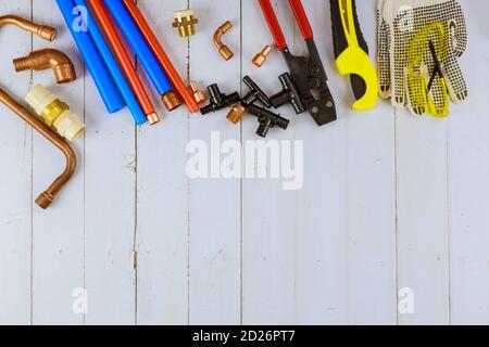 Installation of plastic pipes for the water system, pipe cutting tools, corners, holders, taps, adapters and work gloves on equipment for plumbing at construction site Stock Photo