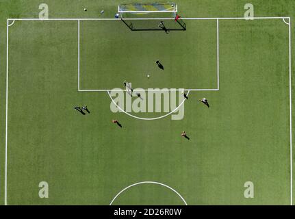 Soccer players playing a match on a green sports field viewed directly from overhead from a drone on a sunny summer day Stock Photo