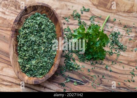 dried rubbed and fresh parsley on olive wood Stock Photo