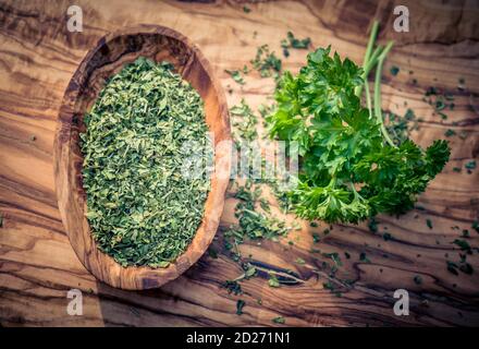 dried rubbed and fresh parsley on olive wood Stock Photo