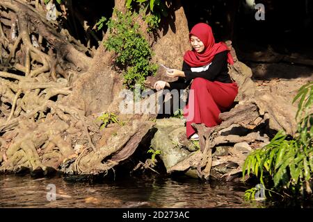 portrait of an asian woman feeding fish in a pond. holiday in koi fish ponds on weekends Stock Photo