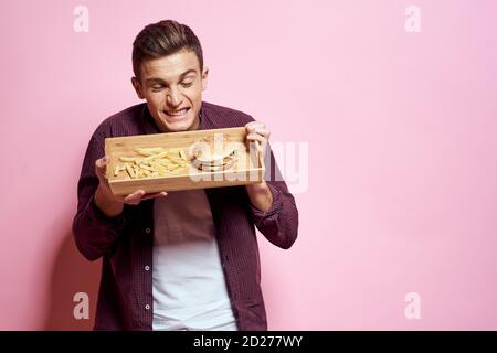 Man with wooden pallet fast food diet food lifestyle pink background Stock Photo