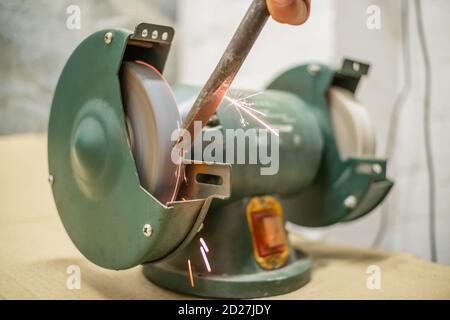 master sharpens a chisel on a grinding machine Stock Photo