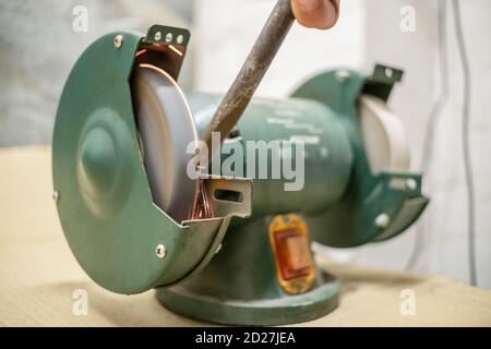 master sharpens a chisel on a grinding machine Stock Photo