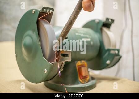 master sharpens a chisel on a grinding machine Stock Photo