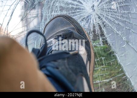 Leg on the background of the broken windshield of the car. Cracked windshield after the accident. Kick on the windshield Stock Photo