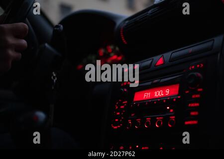 Driver's hands on the steering wheel of the car, drive at night by car. Focus on the red illuminated car console Stock Photo