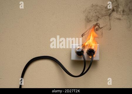 On fire electric wire plug Receptacle on the concrete wall background Stock Photo
