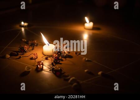 pentagram is painted on the floor, candles are lit, beads are lying, shells are scattered. concept of magic with occult and esoteric symbols. Stock Photo