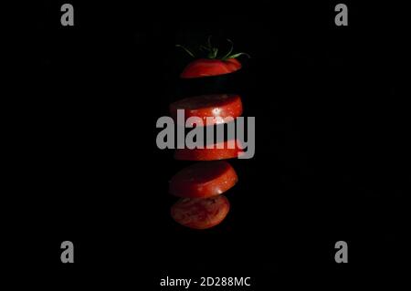 Sliced red tomato in the air on a black background, close-up. High quality photo Stock Photo