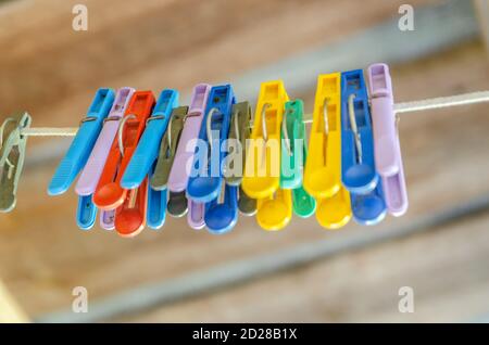 old colored plastic clothespins hanging in a row on the washing line, close up with shallow depth of field and copy space Stock Photo