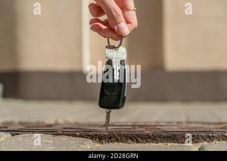 Close-up of girl's hand with car keys above the hatch. Someone dropped the keys, the girl picked up the keys Stock Photo