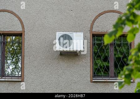 air conditioner outdoor unit compressor installed outside the house on the wall near the windows Stock Photo