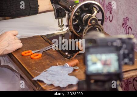 Old vintage sewing machine closeup. blogger on camera with a tripod shoots a report about the sewing business Stock Photo