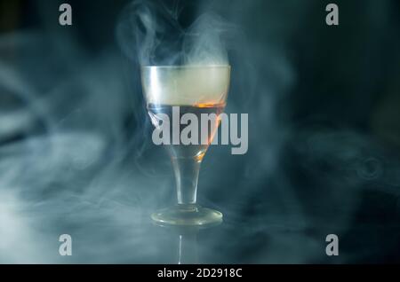 glass of cognac in the smoke on a black background Stock Photo