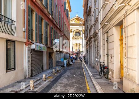 A narrow alley with cafe with a view of the Baroque Church of Saint Francois de Paule in the Cours Saleya area of Old Town Nice France. Stock Photo