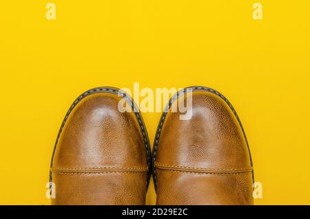 Rounded nose of men's brown shoes on a yellow background close-up with a copy of the space Stock Photo