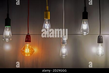Light bulbs with multi-colored electric cords on a dark background. Stock Photo