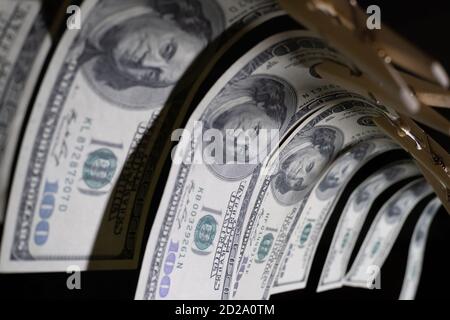 One-hundred dollar bills are hung with clothespins on a string on a black background. concept of dirty money. dollar is falling, close up Stock Photo