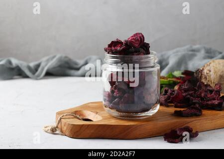 Beet chips in glass jar and wooden board on light background. Copy space. Stock Photo