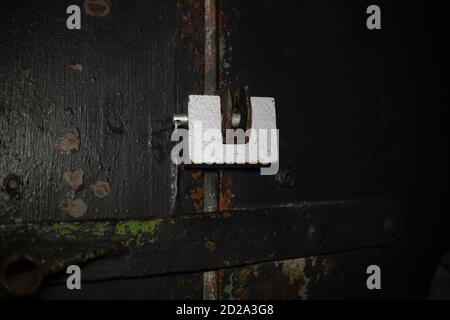 Steel lock hanging on the door of an old garage in the dark, copy space Stock Photo
