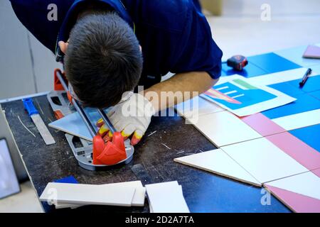 A man cuts ceramic material with a tile cutter, close-up Stock Photo