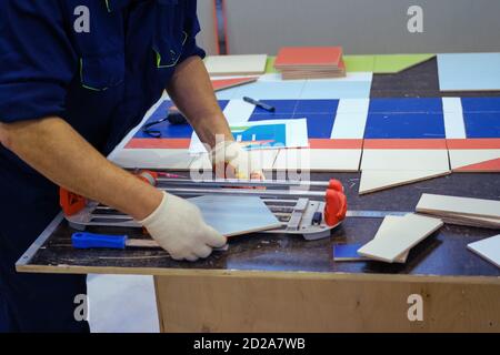 Worker cuts ceramic material with a professional tile cutter Stock Photo